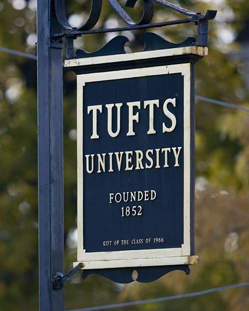 A Tufts University sign near fall foliage.