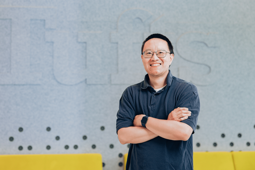 Ming Chow, Tufts computer science professor standing next to Tufts sign