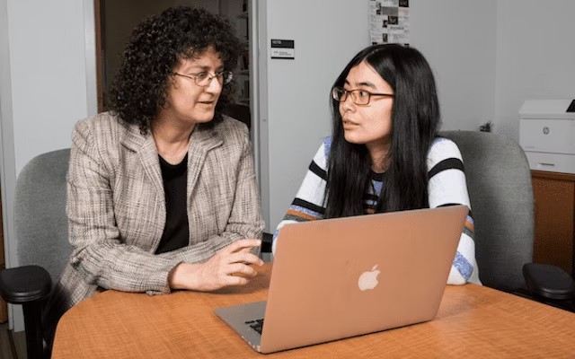 A Tufts University faculty member and student at work at a laptop.