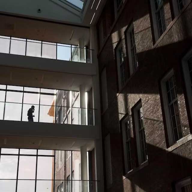 	A student in silhouette walks inside a Tufts University building. 