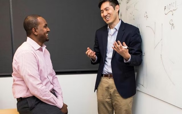 Kyongbum Lee talks to a student in a classroom.