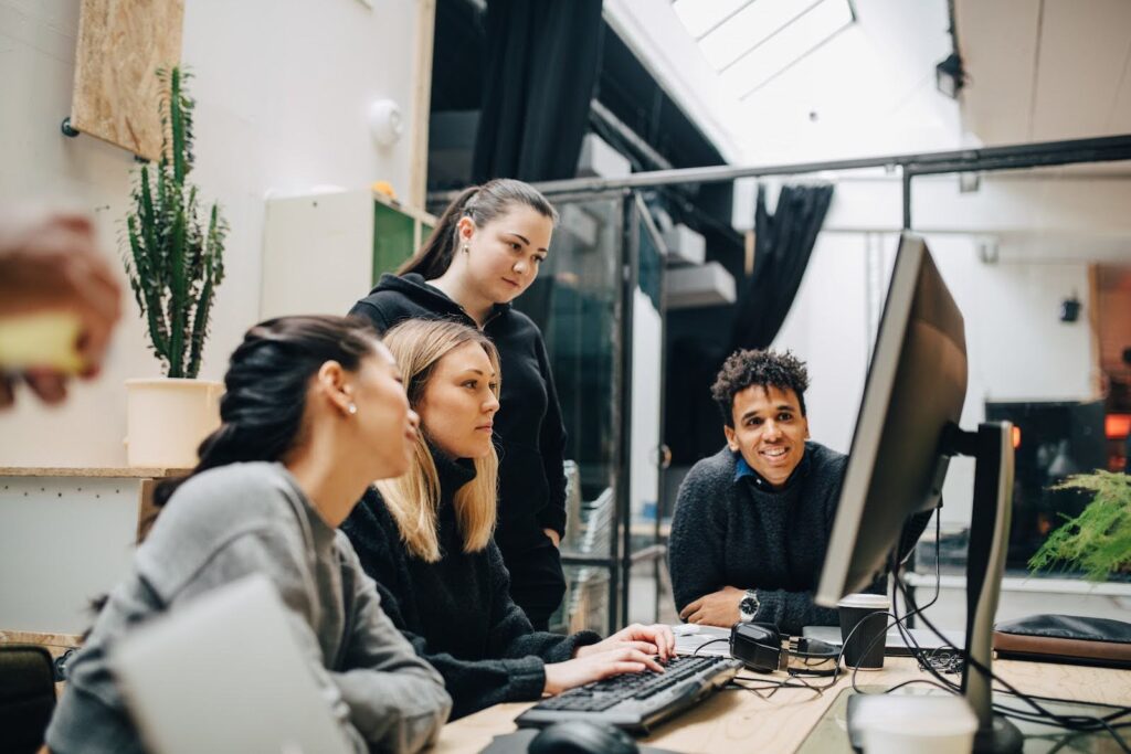 Four students collaborate on a computer science project at a desktop workstation.