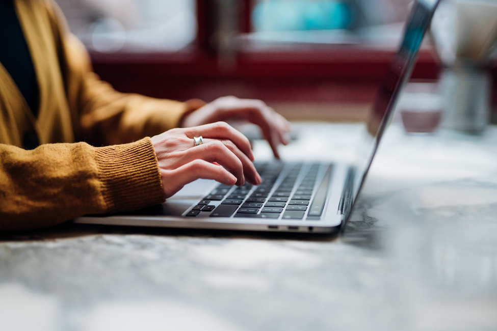 Close up of hands typing on a laptop computer.