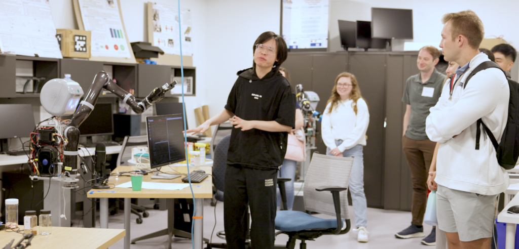 A student demonstrates a project to peers in a robotics lab.