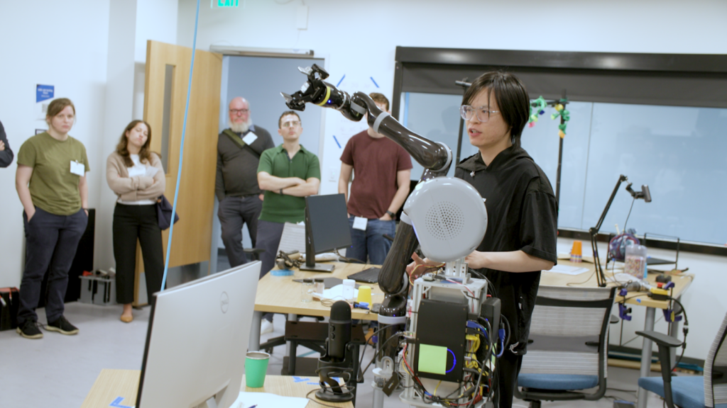 A student in the Tufts Assistive Agent Behavior and Learning Lab demonstrates a robotics project to fellow students and faculty.